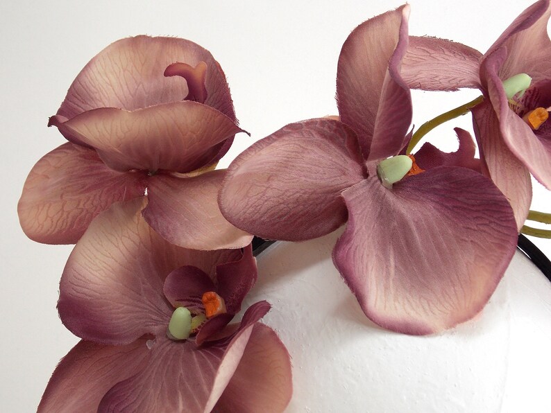 May include: A cluster of mauve silk orchid flowers with green centers. The flowers are arranged in a bouquet and are ready to be used for crafting or decorating.