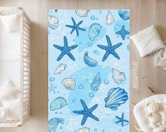 May include: A blue and white patterned rug featuring starfish and seashells. The rug has a light blue background with scattered blue starfish and white seashells. The design is reminiscent of a beach or ocean theme.