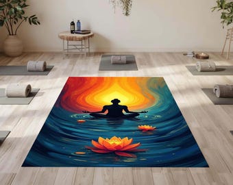 Pode incluir: Um estúdio de ioga com vários tapetes cinzentos e toalhas enroladas. Um grande tapete de ioga no centro apresenta uma ilustração colorida de uma pessoa a meditar na água, com uma flor de lótus. O fundo tem plantas e uma pequena mesa.