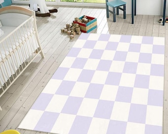May include: A rectangular area rug with a checkerboard pattern of alternating white and light purple squares. The rug is placed on a light-colored wooden floor in a child's room setting.