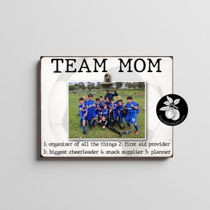 以下が含まれることがあります： 「TEAM MOM」という文字と、青いユニフォームを着た少年サッカーチームの写真が書かれた白い木製の看板。看板には、「1: 全ての事をまとめる人 2: 救急隊員 3: 最大のチアリーダー 4: スナックの供給者 5: プランナー」という文章も書かれている。