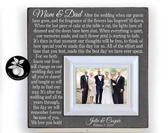 May include: A gray wooden sign with a white frame and a photo of a wedding party. The sign has a message for parents of the bride and groom that reads "Mom & Dad After the wedding when our guests have gone, and the fragrance of the flowers has lingered 'til dawn. When the last piece of cake at the table is cut, the lights have all dimmed and the doors have been shut. When everything is quiet, our memories made, and each flower petal is starting to fade. It's then in that moment our thoughts will be free, to think of how special you've made this day for us. All of the effort and time that you lent, made this the best day we have ever spent. For we both know our lives will change on our wedding day, and all you've shared and taught us will help us find our way. It's after the wedding and all the years through, this day we will remember forever because of you. We love you both!" The sign also includes the names "Julie & Cooper" and the date "October 5, 2019".