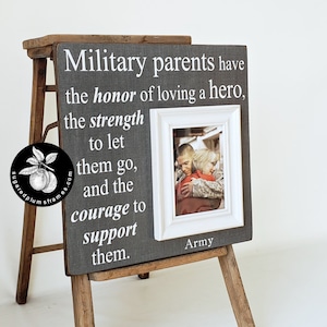 May include: A grey wooden picture frame with a white mount and a white frame inside. The frame has a quote about military parents and a photo of a soldier hugging a woman. The text on the frame reads: "Military parents have the honour of loving a hero, the strength to let them go, and the courage to support them." The text "Army" is printed below the photo.