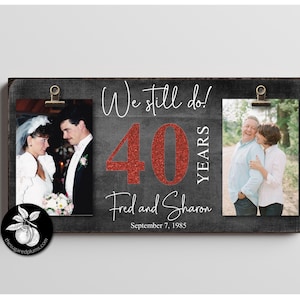 Op de afbeelding: Een rustiek houten bord met twee fotogleuven, ter ere van een 40e huwelijksverjaardag. Het bord heeft de tekst "We still do! 40 YEARS Fred and Sharon September 7, 1985" met een rode glitter 40.