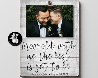 May include: A white wood sign with a black and white photo of a couple in a wedding setting. The sign says "Grow old with me the best is yet to be" and "Adam and John August 24, 2025".