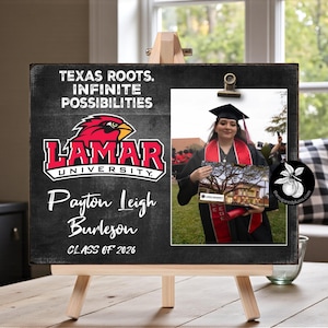 May include: A wooden easel holding a chalkboard-style sign with the text "Texas Roots. Infinite Possibilities" and the Lamar University logo. A photograph of a graduate is clipped to the sign. The sign also includes the name "Payton Leigh Burleson" and "Class of 2026."