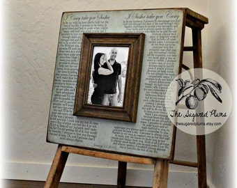 May include: A wooden frame with a black and white photo of a couple. The frame is decorated with a printed text that reads "I Casey take you Sasha" and "I Sasha take you Casey". The frame is on a wooden easel.