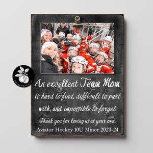 May include: A wooden framed photo with a team photo of hockey players in red jerseys and helmets. The frame has text that reads "An excellent Team Mom is hard to find, difficult to part with, and impossible to forget."