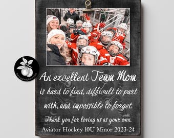 May include: A wooden framed photo with a team photo of hockey players in red jerseys and helmets. The frame has text that reads "An excellent Team Mom is hard to find, difficult to part with, and impossible to forget."