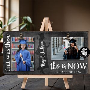 May include: A wooden graduation photo display with two photos, one labeled "that was then" and the other "this is NOW CLASS OF 2026". The display includes the name "Abigail Jackson" and is mounted on a small wooden easel.