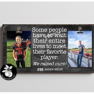 May include: A black framed sign with a chalkboard background and two photos of a young man in a football uniform. The text on the sign reads "Some people have to wait their entire lives to meet their favorite player. We raised ours! #20 JAIDEN SEELYE"