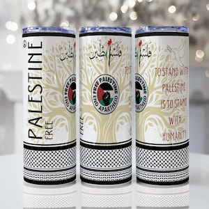 May include: Three white insulated tumblers with black lids. Each tumbler features the words "PALESTINE FREE" in English, Arabic text, and a tree design. The tumblers also have a black and white checkered pattern at the base and the text "TO STAND WITH PALESTINE IS TO STAND WITH HUMANITY".
