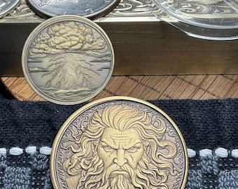 May include: A collection of coins, including a silver coin with a depiction of a wolf, and a gold-toned coin featuring a detailed portrait of a bearded man. The coins are displayed on a wooden surface with a patterned cloth.