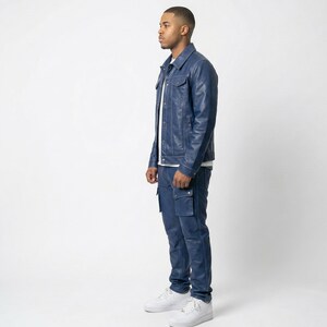 May include: A person wearing a navy blue leather jacket and matching cargo pants. The jacket has two chest pockets and a button-down front. The pants have two cargo pockets on the thighs. The person is wearing white sneakers.