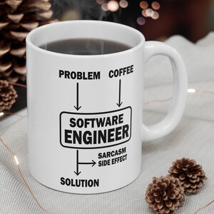 Peut inclure: Tasse à café en céramique blanche remplie de liquide foncé, avec le texte "Problem Coffee Software Engineer Solution Sarcasm Side Effect". La tasse a une anse blanche. Des éléments décoratifs entourent la tasse.