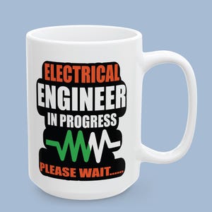 Peut inclure: Un mug en céramique blanc avec le texte "ELECTRICAL ENGINEER IN PROGRESS" en lettres noires et orange, accompagné d'un graphique en forme d'onde électrique dentelée verte et blanche et du texte "PLEASE WAIT....." inscrit en bas.