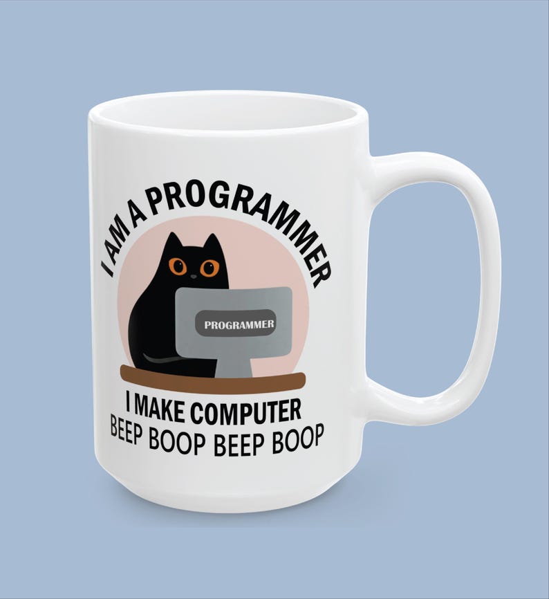 Op de afbeelding: Een witte keramische mok met een afbeelding van een zwarte kat die achter een computer zit. De tekst I AM A PROGRAMMER staat boven de kat en I MAKE COMPUTER BEEP BOOP BEEP BOOP eronder. Het computerscherm toont het woord PROGRAMMER.