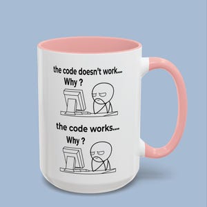 May include: A white ceramic mug with a soft pink interior and handle. The mug features two black line-art illustrations of a person at a computer with the text: the code doesn't work.... Why? and the code works.... Why?