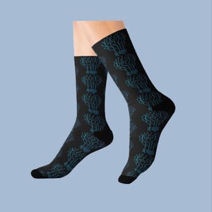 May include: A pair of black crew socks featuring a repeating light blue circuit board pattern. The design consists of interconnected lines and nodes that resemble a digital network or motherboard layout, covering the entire surface of the socks.