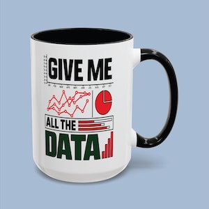 Może przedstawiać: Biały ceramiczny kubek z czarnym wnętrzem i uchwytem. Z przodu znajduje się napis GIVE ME ALL THE DATA w kolorze czarnym i zielonym, któremu towarzyszą czerwone wykresy liniowe, czerwony wykres kołowy oraz czerwony wykres słupkowy z danymi.