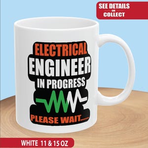 May include: White ceramic mug with the text "ELECTRICAL ENGINEER IN PROGRESS PLEASE WAIT..." in black, orange, and green. The mug has a curved handle and is labeled "WHITE 11 & 15 OZ".