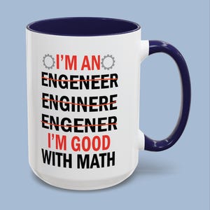 May include: A white ceramic mug with a dark blue interior and handle. The front features the text I'M AN ENGENEER, ENGENEER, ENGINERE, ENGENER, I'M GOOD WITH MATH in black and red, with red strikethrough lines and two small grey gear icons.