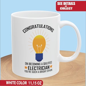 Könnte beinhalten: Weiße Keramik-Tasse mit Henkel. Die Tasse zeigt den Text "CONGRATULATIONS" über einem gelben Glühbirnen-Design mit blauen Akzenten. Darunter steht "ON BECOMING A QUALIFIED ELECTRICIAN YOU'RE SUCH A BRIGHT SPARK". Die Tasse fasst etwa 330 ml.