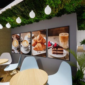 May include: A cafe interior featuring four framed art prints showcasing coffee, croissants, and cake. The cafe has light blue chairs, wooden tables, and hanging globe lights. Greenery hangs from the ceiling, creating a welcoming atmosphere.
