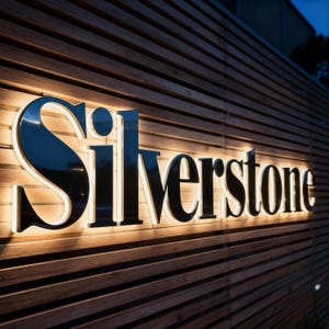 Puede incluir: Un letrero tridimensional con la palabra Silverstone en letras grandes, negras y con serifa. Las letras est&aacute;n montadas sobre una pared de listones de madera horizontales y est&aacute;n iluminadas desde atr&aacute;s con un brillo blanco c&aacute;lido.