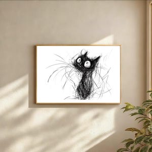 Könnte beinhalten: Ein gerahmter Kunstdruck mit einer skizzierten schwarzen Katze mit großen Augen und langen Schnurrhaaren. Das Kunstwerk befindet sich vor einem weißen Hintergrund, ist in einem goldfarbenen Rahmen gefasst und an einer beigefarbenen Wand montiert.