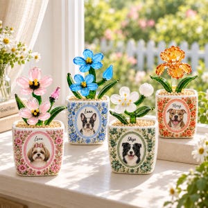 May include: Four square ceramic planters featuring floral patterns and portraits of dogs named Luna, Luna, Skye, and Roxy. Each planter holds a glass flower sculpture with green stems and colorful petals, sitting on a light surface near a window.