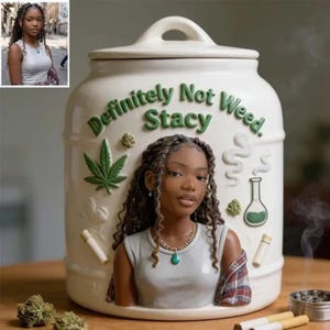 Peut inclure: Un bocal de rangement en céramique crème avec couvercle, orné d'un relief représentant une personne aux longs cheveux tressés portant un débardeur blanc et une chemise à carreaux. Le bocal porte le texte vert "Definitely Not Weed. Stacy" et des feuilles.