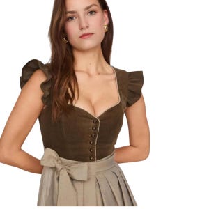 May include: A brown corduroy bodice with a sweetheart neckline and ruffled sleeves. The bodice has a row of buttons down the front and is paired with a beige skirt with a bow at the waist. The outfit is a traditional style.
