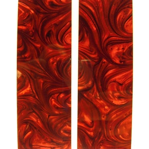 May include: Two red and black marbled rectangular pieces of wood. The wood has a swirling pattern and a glossy finish.