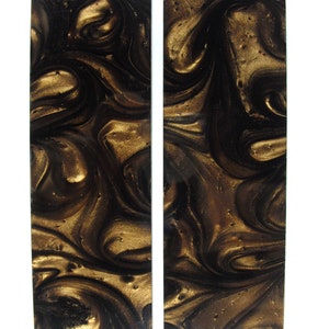 May include: Two black and gold marbled rectangular pieces of resin. The resin has a swirling pattern with gold flecks.