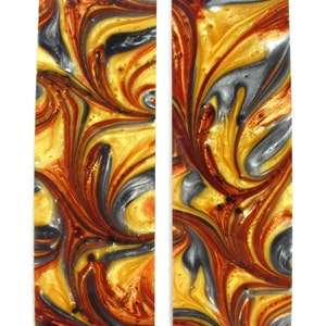 May include: Two pieces of marbled resin, one gold, silver, and brown, the other gold, silver, and red. The resin is swirled and has a glossy finish.