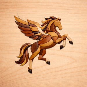 May include: A wooden Pegasus sculpture with a light brown, medium brown, and dark brown color scheme. The winged horse is leaping, with its front legs raised. The wings are multi-toned, and the sculpture is set against a light wood background.