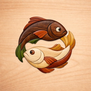 Peut inclure: Une décoration murale en bois représentant deux poissons disposés en cercle. Le poisson supérieur est en bois brun foncé avec des nageoires orange, tandis que le poisson inférieur est en bois beige clair avec des nageoires brun-rouge et des détails verts.