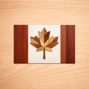 May include: A wooden Canadian flag with a maple leaf design. The flag has a white central panel with a multi-toned maple leaf. Vertical red stripes flank the white panel, and the background is a light wood grain.