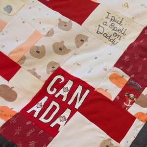 Puede incluir: Un edredón de retazos con varios patrones y colores de tela. El edredón presenta cuadrados con estampados de osos, la palabra "CANADA" y la frase "I put a Spell on Daddy". Otros cuadrados tienen diseños de calabazas y hojas.