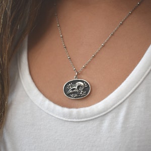 May include: A silver chain necklace with a pendant featuring a detailed skull with floral accents.