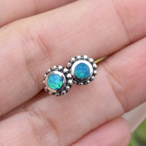 May include: A pair of silver stud earrings with round blue opal gemstones.