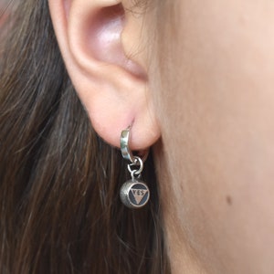 May include: Silver hoop earrings with a small silver charm that says "YES" in black lettering.