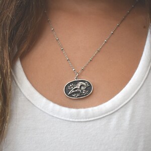 May include: A silver chain necklace with a pendant featuring a detailed skull design with floral accents.