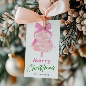 May include: A white gift tag featuring a pink watercolour Christmas tree design and a pink bow. The tag reads "Merry Christmas" in pink and green, with "Love, The Smiths" below. It's tied with a light pink ribbon.