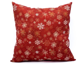 May include: Red throw pillow with a white snowflake pattern. The snowflakes are scattered across the pillow and are a festive design.