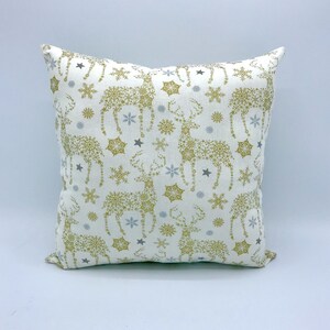 May include: A white throw pillow with a gold and silver snowflake and reindeer pattern.