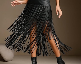 May include: A black faux leather midi skirt featuring a high-waisted design with a metallic buckle detail on the side. The skirt is adorned with long, thin black fringe strips that extend from the waist down to the hem, creating a layered effect.