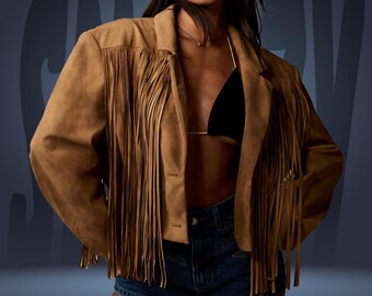 Könnte beinhalten: Braune Wildlederjacke mit langen Fransen. Die Jacke hat einen klassischen Kragen und einen Knopfverschluss. Das Model trägt ein schwarzes Bikinioberteil und Jeansshorts.