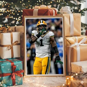 May include: Framed photo of a football player in a green and yellow uniform, with the number 1. The player is making a hand gesture. The photo is surrounded by wrapped gifts and Christmas lights.